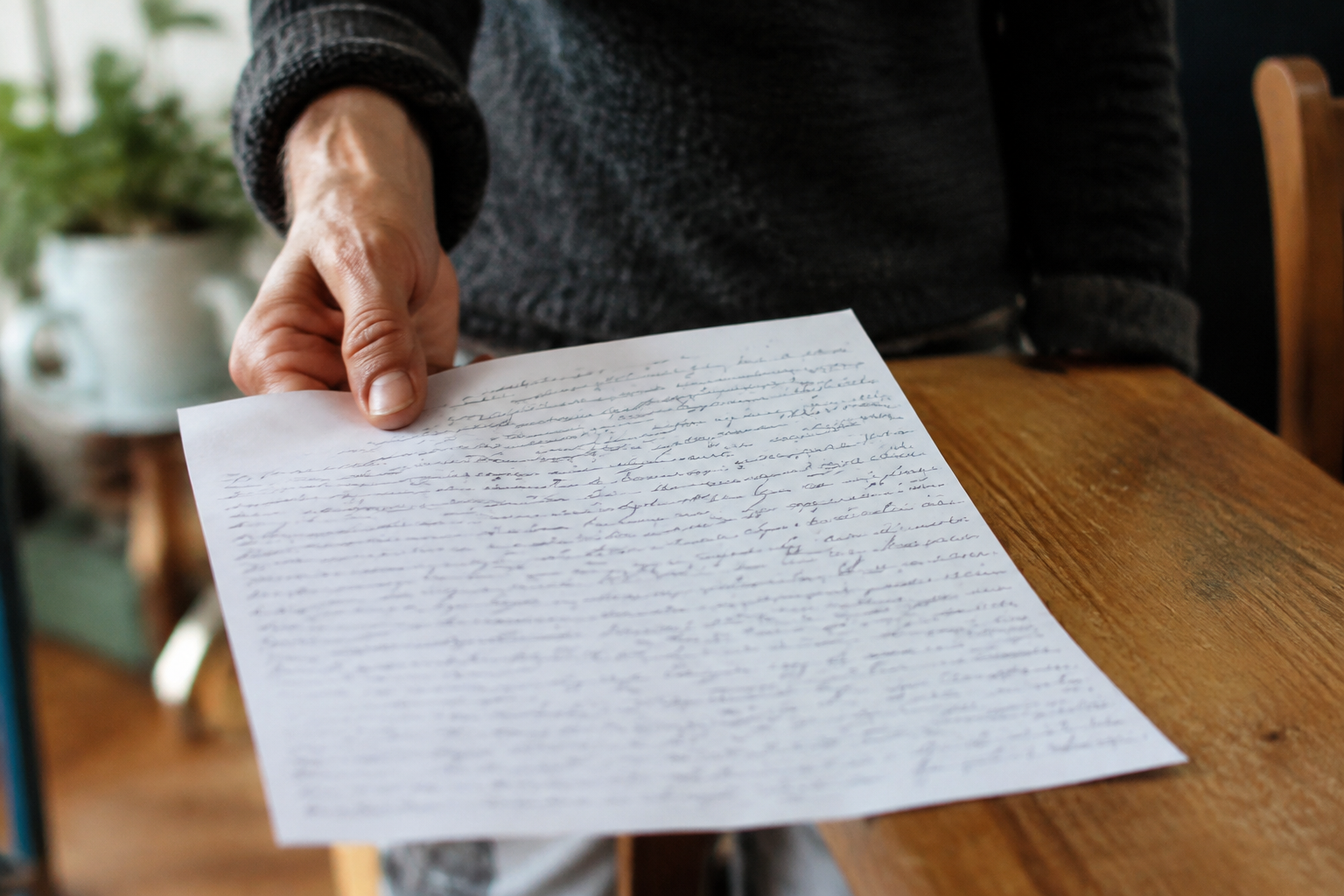 mains tendues presentant papier blanc couvert de texte manuscrit