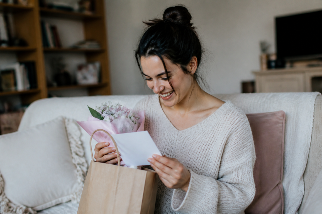 Femme tenant message manuscrit avec fleur et cadeau